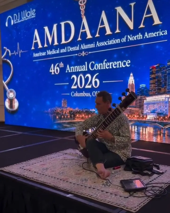 Sitar performance on stage in front of a large LED screen